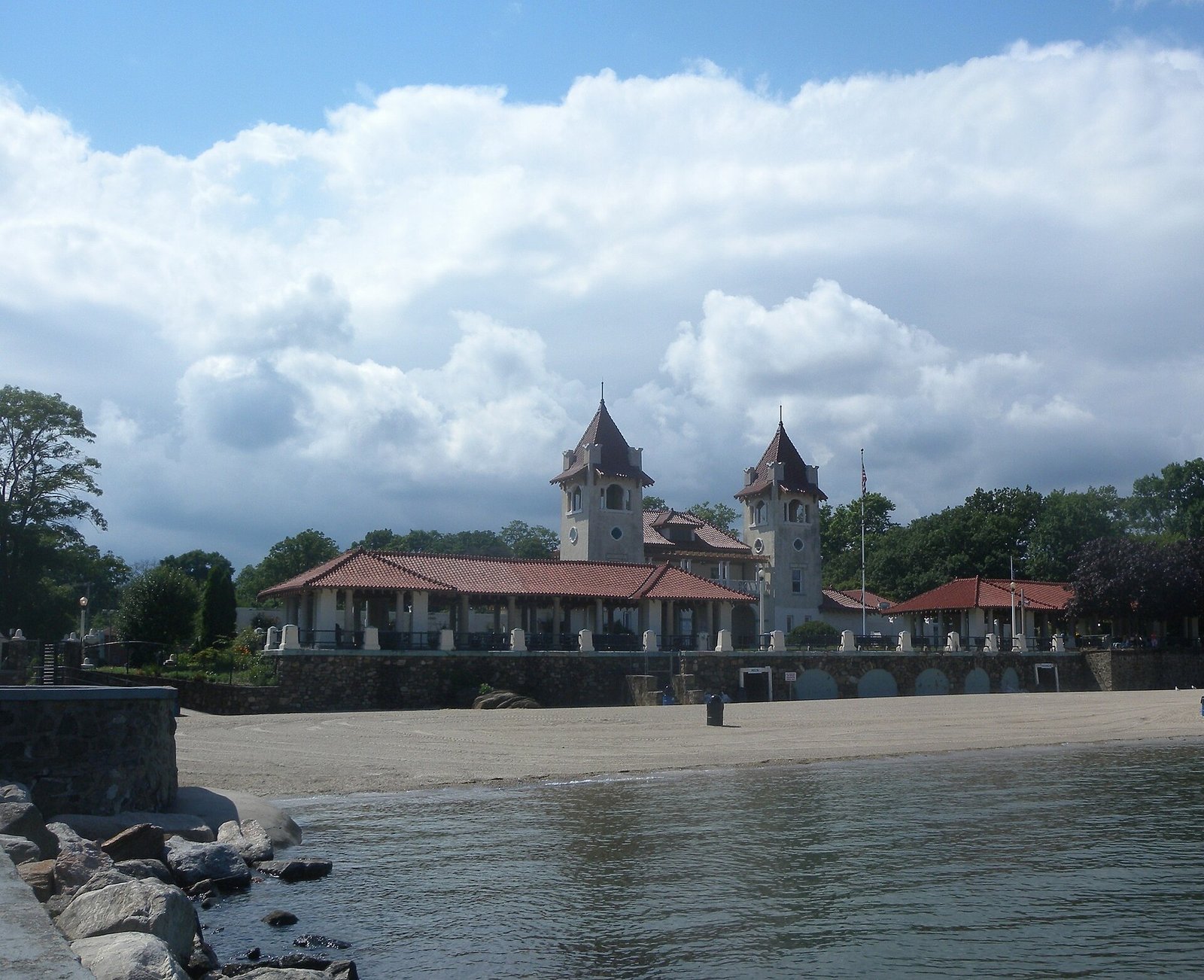 Empty historic Rye Town Park bathhouse with twin towers and terracotta roofs overlooking a sandy beach and Long Island Sound, Rye, NY